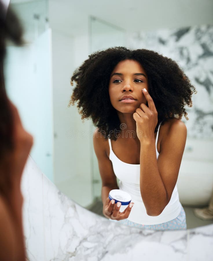 Hydrating Her Skin First Thing In The Morning An Attractive Young Woman Applying Moisturizer To