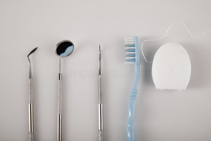Hygiene of Teeth Concept with Toothbrush, Dental Floss and Dental Tools on a Grey Background