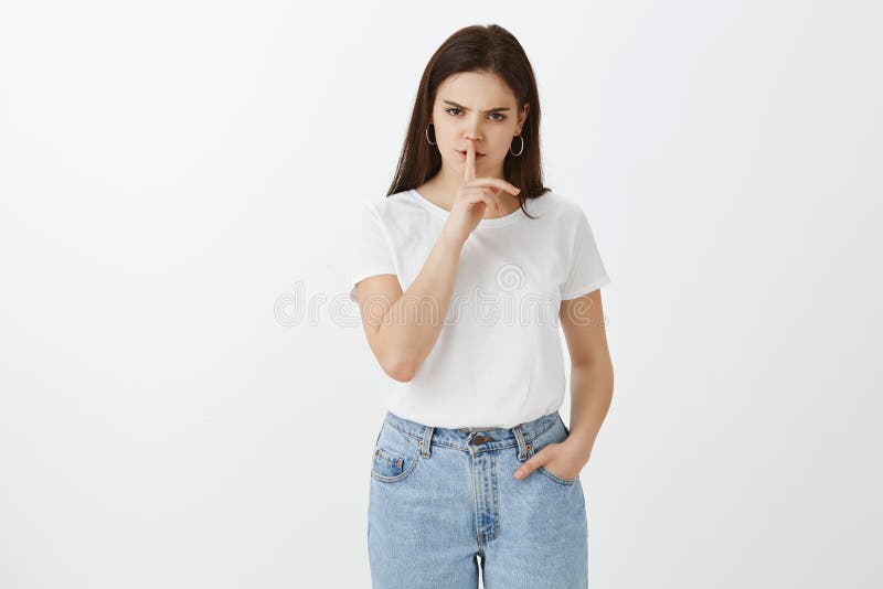 Hyssja ner uppehälletystnaden, endast viskning Allvarlig irriterad stilfull europeisk kvinna i jeans och t-skjortan som rymmer ha royaltyfria foton Hyssja ner uppehälletystnaden, endast viskning Allvarlig irriterad stilfull europeisk kvinna i jeans och t-skjortan som rymmer ha royaltyfria foton