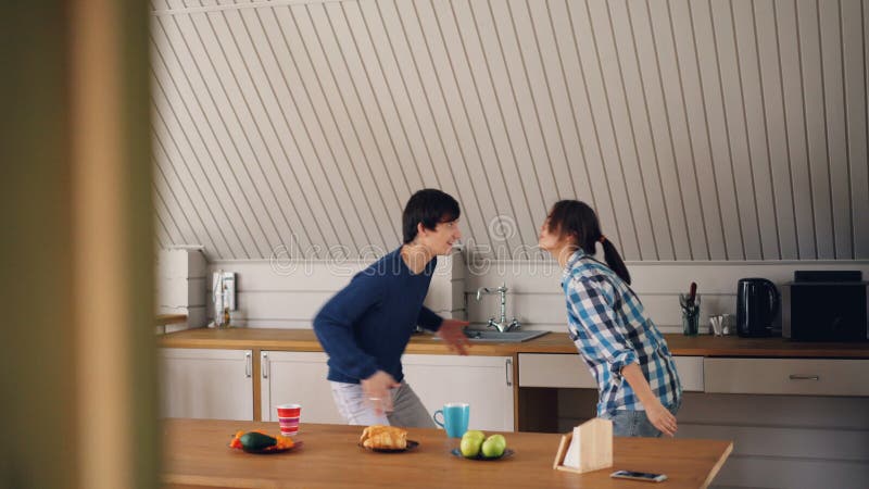 Hübscher asiatischer Kerl tanzt zu Hause mit seiner netten Freundin, die Spaß hat und in der Küche küsst, die bequeme Kleidung tr