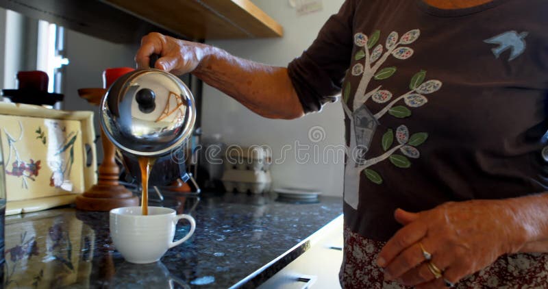 Hällande kaffe för hög kvinna in i kaffekoppen i kök 4k