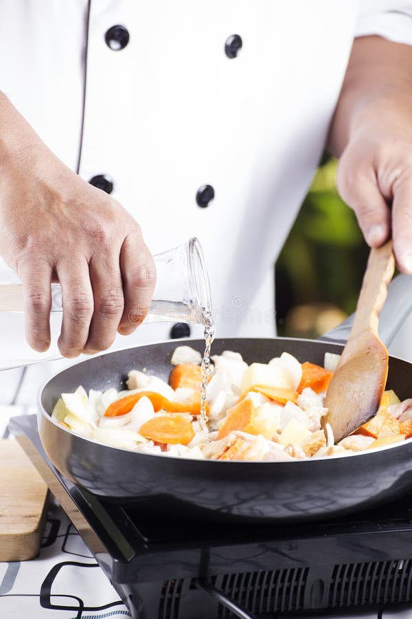 Chef pouring soup to the pan for cooking Japanese pork curry / cooking Japanese pork curry paste concept. Chef pouring soup to the pan for cooking Japanese pork curry / cooking Japanese pork curry paste concept