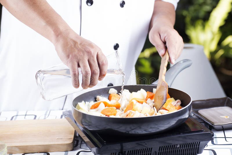 Chef pouring soup to the pan for cooking Japanese pork curry / cooking Japanese pork curry paste concept. Chef pouring soup to the pan for cooking Japanese pork curry / cooking Japanese pork curry paste concept