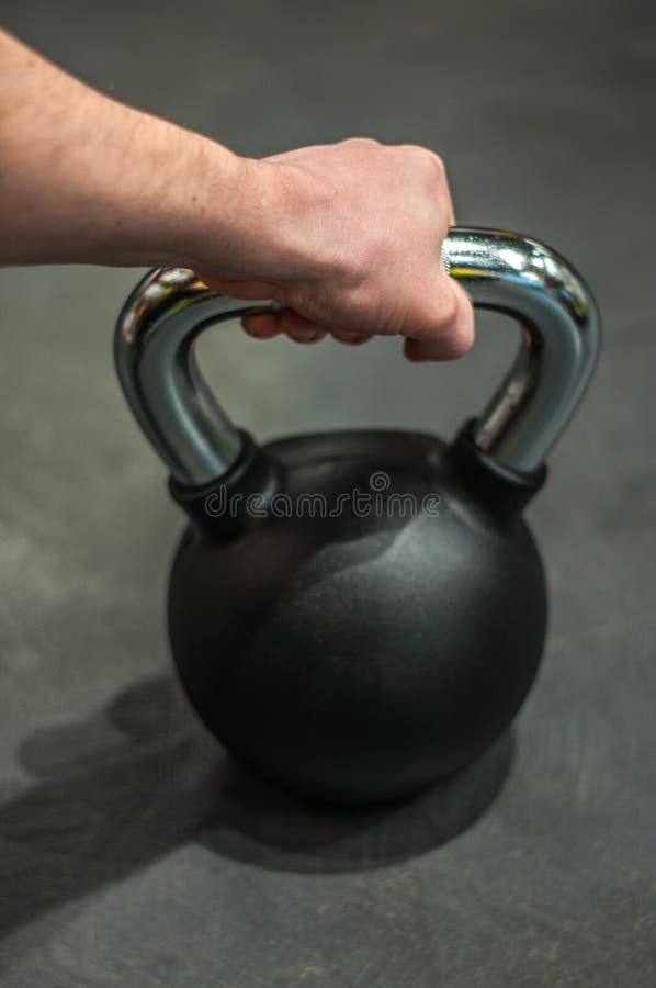Hälso- och sportlivsstilbegreppet, en man rymmer en svart metallkettlebellvikt i en rubber skida fotografering för bildbyråer