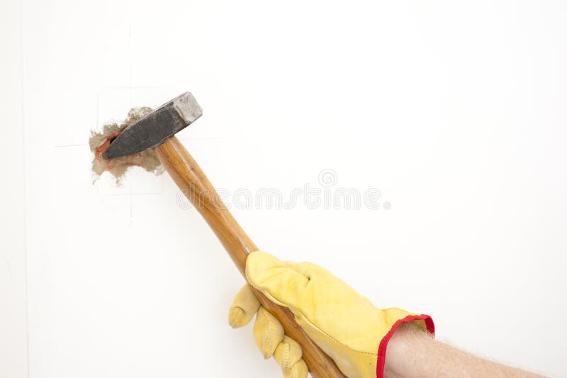 Hammer in hand with gloves of man smashing hole in white home brick wall, demolishing, damaging house room, isolated with white background and copy space. Hammer in hand with gloves of man smashing hole in white home brick wall, demolishing, damaging house room, isolated with white background and copy space.