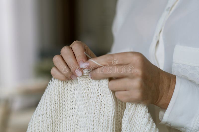 Woman&#x27;s hands knitting brown wool yarn pattern. Closeup horizontal photo. Freelance creative handicraft concept, hobby and lifestyle. Woman&#x27;s hands knitting brown wool yarn pattern. Closeup horizontal photo. Freelance creative handicraft concept, hobby and lifestyle