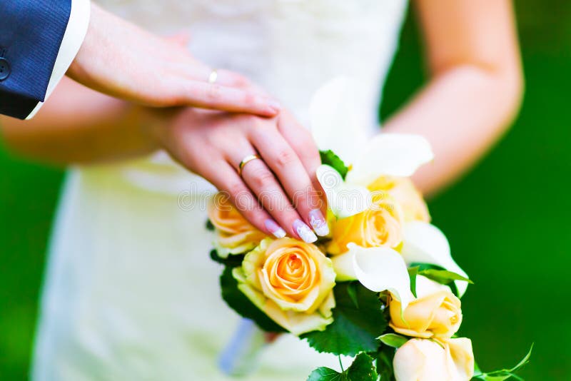 Macro view of the hands of married couple of bride and groom with golden wedding rings with selective focus effect. Macro view of the hands of married couple of bride and groom with golden wedding rings with selective focus effect