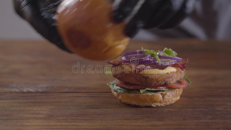 Hände des Chefs, der Burgernahaufnahme macht Geschmackvolle Lebensmittelzubereitung