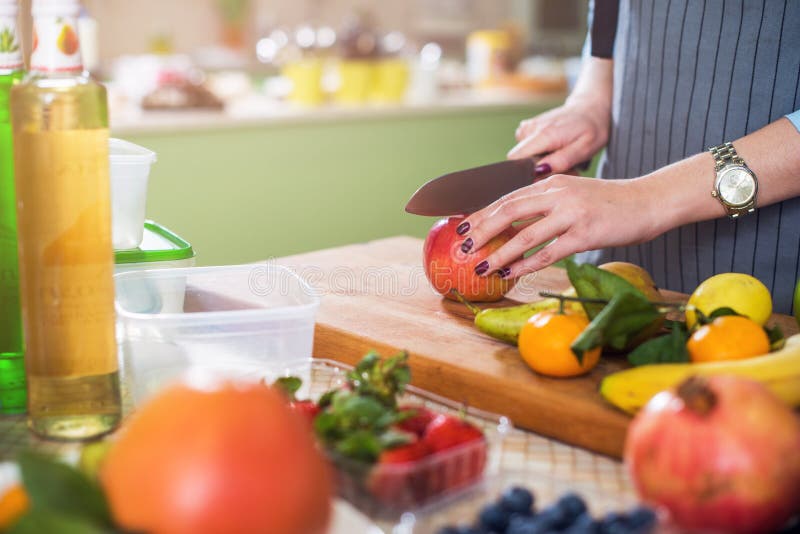 Hände, die einen Apfel auf hackendem Brett schneiden Junge Frau, die einen Obstsalat in ihrer Küche zubereitet stockbild Hände, die einen Apfel auf hackendem Brett schneiden Junge Frau, die einen Obstsalat in ihrer Küche zubereitet stockbild