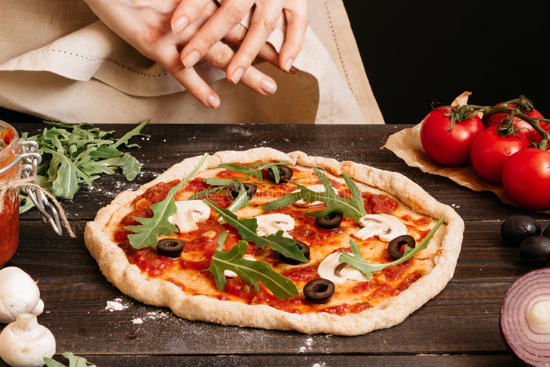 Hände, die Pizza in der Küche kochen Pizzabestandteile auf dem Holztisch stockfotografie Hände, die Pizza in der Küche kochen Pizzabestandteile auf dem Holztisch stockfotografie