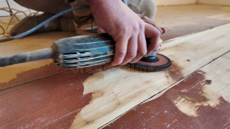Hände eines Handwerkers mit Schleifwerkzeug für das Deichen auf einem Parkettboden aus Holz. Rekonstruktion des Holzbodens.
