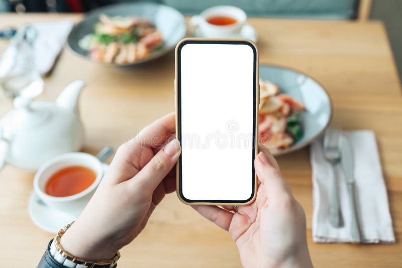 Hände mit einem Bildschirm auf dem Hintergrund des Essens in einem Café. Ort für Ihre Rezension oder Ihr Menü lizenzfreie stockfotografie
