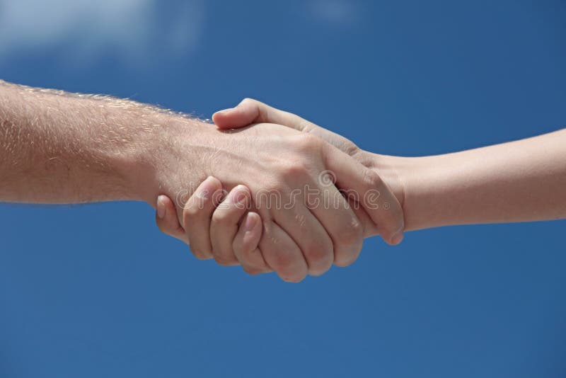 A man and woman handshaking in front of a bright blue sky. A man and woman handshaking in front of a bright blue sky