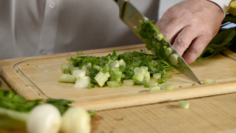 Händer av det stora köket för kockkniv nya gröna lökar för en fjäder på en skärbräda från ett träd