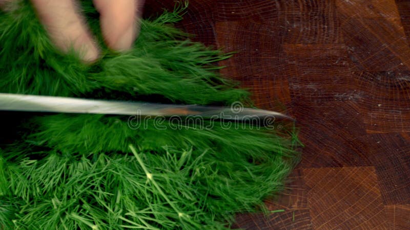 Händer med knivslipning av gröna dillsprickor med vassa knivar för matlagning.