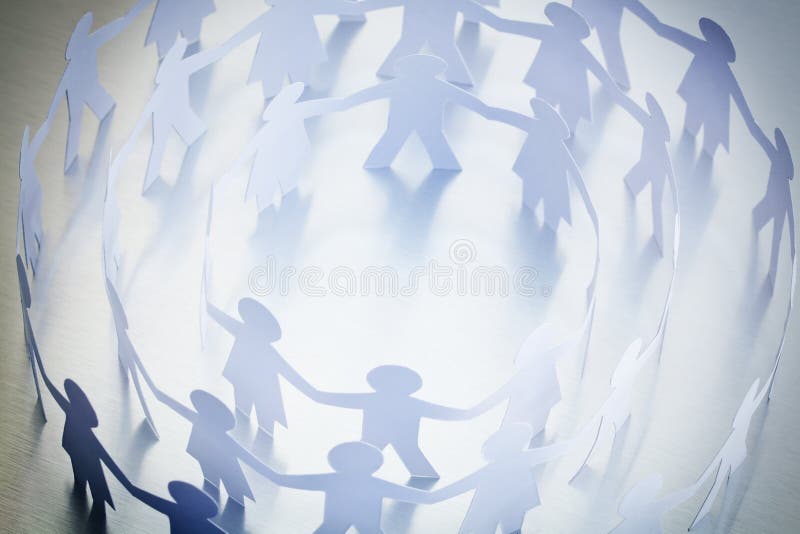 Overhead view of concentric circles of paper people holding hands; business concept. Overhead view of concentric circles of paper people holding hands; business concept.