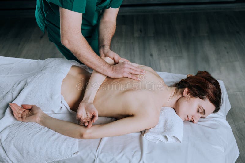 Händerna av en manlig massör som gör massage av en ung kvinna Härlig avkopplad framsida av en ung kvinna 27 gamla år med brun hai arkivfoto Händerna av en manlig massör som gör massage av en ung kvinna Härlig avkopplad framsida av en ung kvinna 27 gamla år med brun hai arkivfoto