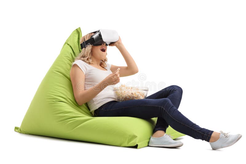 Häpen kvinna som placeras på en sittkudde genom att använda en VR-hörlurar med mikrofon royaltyfri fotografi Häpen kvinna som placeras på en sittkudde genom att använda en VR-hörlurar med mikrofon royaltyfri fotografi