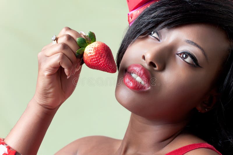 Beautiful young black woman eating a strawberry, closeup shot. Beautiful young black woman eating a strawberry, closeup shot