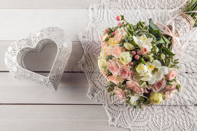 Härlig bröllopbukett av rosor och freesia med hjärta på vit träbakgrund, bakgrund för valentin eller bröllopdag royaltyfria foton Härlig bröllopbukett av rosor och freesia med hjärta på vit träbakgrund, bakgrund för valentin eller bröllopdag royaltyfria foton