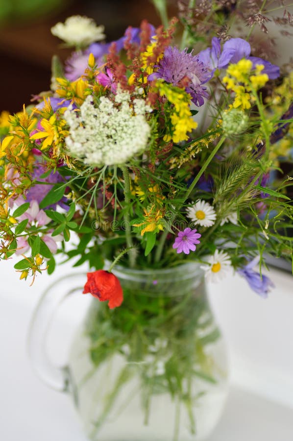 Härlig bukett av ljusa vildblommor i den glass vasen arkivfoton Härlig bukett av ljusa vildblommor i den glass vasen arkivfoton