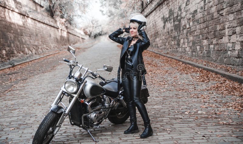 Härlig cyklistkvinna som är utomhus- med motorcykeln royaltyfri fotografi Härlig cyklistkvinna som är utomhus- med motorcykeln royaltyfri fotografi