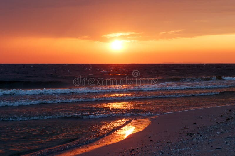 Härlig guld- solnedgång i havet med genomdränkt himmel och moln Reflexion i vattnet Stenig kust- linje Fridsamt fridfullt LAN royaltyfri fotografi Härlig guld- solnedgång i havet med genomdränkt himmel och moln Reflexion i vattnet Stenig kust- linje Fridsamt fridfullt LAN royaltyfri fotografi