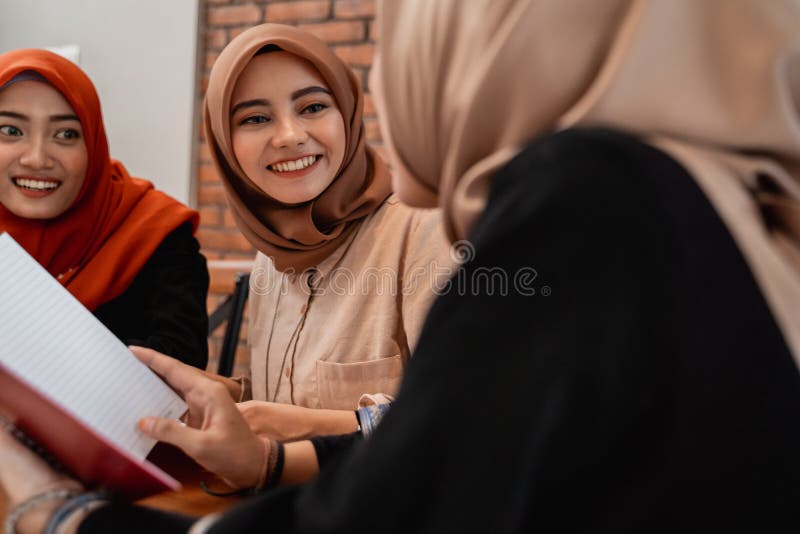 H? rlig hijabkvinna som ler, n? r prata med hennes universitetv? nner royaltyfria bilder