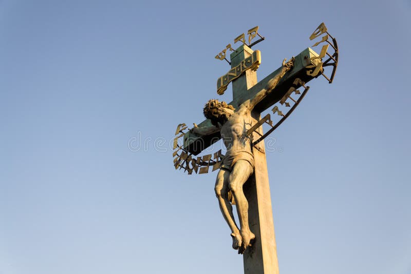 Härlig Jesus Christ korsfästelse brons statyn under soluppgång som är bildhuggar- av St-korset med calvaryen, Charles Bridge, Pra