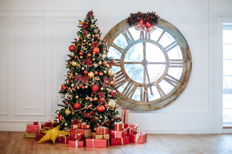Härlig julvardagsrum med den dekorerade julgranen, gåvor framme av whateväggen Träd för nytt år med den röda och guld- dekoren