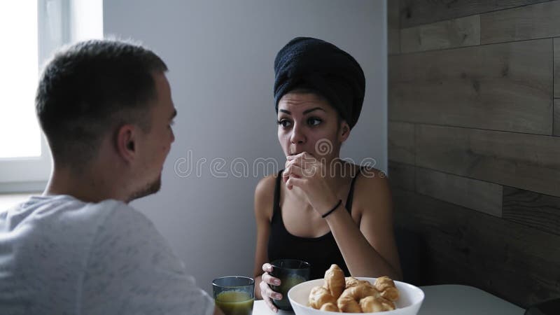 Härlig kvinna efter dusch med den mörka handduken på hennes huvud som äter giffel och dricker kaffe Samtal till hennes pojkvän