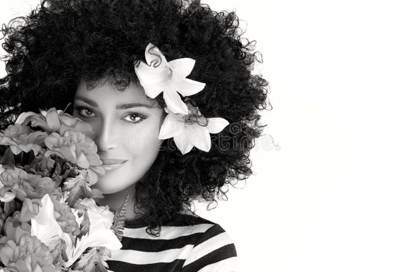 Härlig kvinnaframsida med den lösa lockiga afro- frisyren med blommor arkivfoto Härlig kvinnaframsida med den lösa lockiga afro- frisyren med blommor arkivfoto
