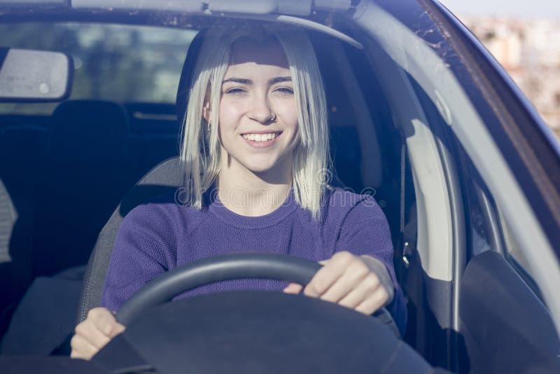 Härlig le kvinna som in kör bilen, attraktivt flickasammanträde royaltyfria bilder