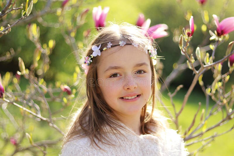Härlig liten flicka med den handgjorda hårkransen på hennes huvud som ler se kameran i den blommande vårträdgården royaltyfri foto Härlig liten flicka med den handgjorda hårkransen på hennes huvud som ler se kameran i den blommande vårträdgården royaltyfri foto