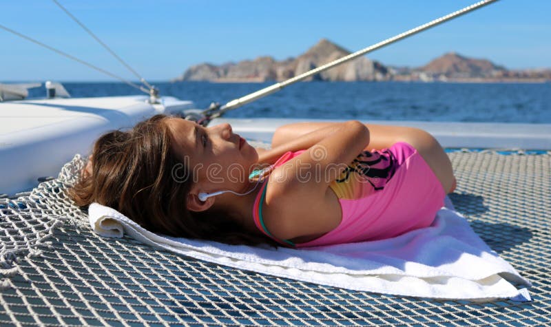 Härlig liten flicka som kopplar av i segelbåt, medan lyssna till musik på havet arkivfoto Härlig liten flicka som kopplar av i segelbåt, medan lyssna till musik på havet arkivfoto