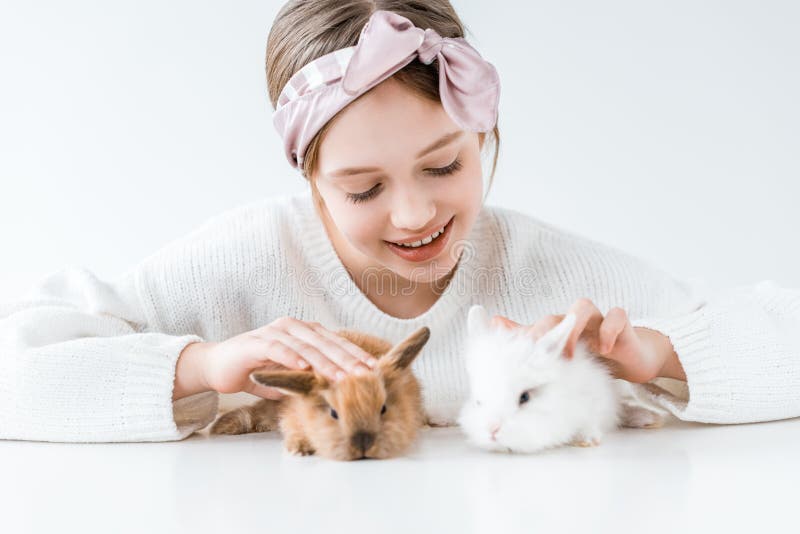 Härlig lycklig flicka som spelar med förtjusande päls- kaniner arkivfoto Härlig lycklig flicka som spelar med förtjusande päls- kaniner arkivfoto