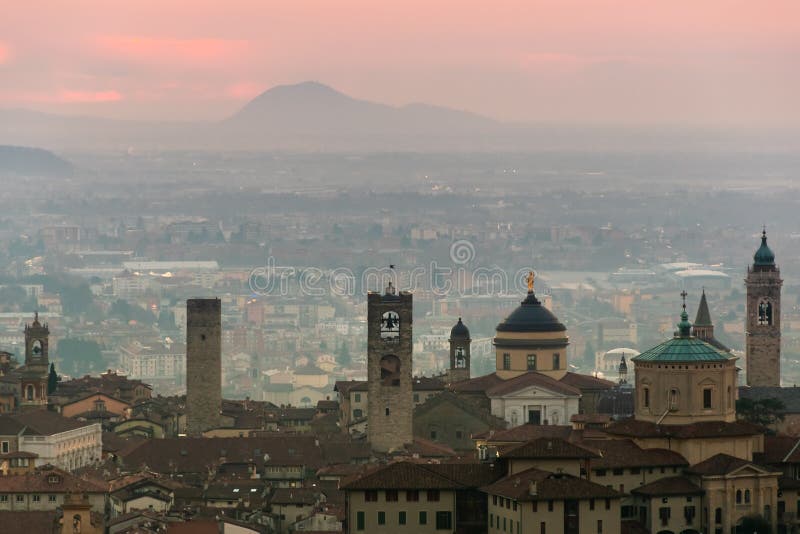 Härlig medeltida stad på soluppgångmorgonen med huvudsakliga sikt av Bergamo Lombardy från Castello di San Vigilio, Italien royaltyfri bild Härlig medeltida stad på soluppgångmorgonen med huvudsakliga sikt av Bergamo Lombardy från Castello di San Vigilio, Italien royaltyfri bild