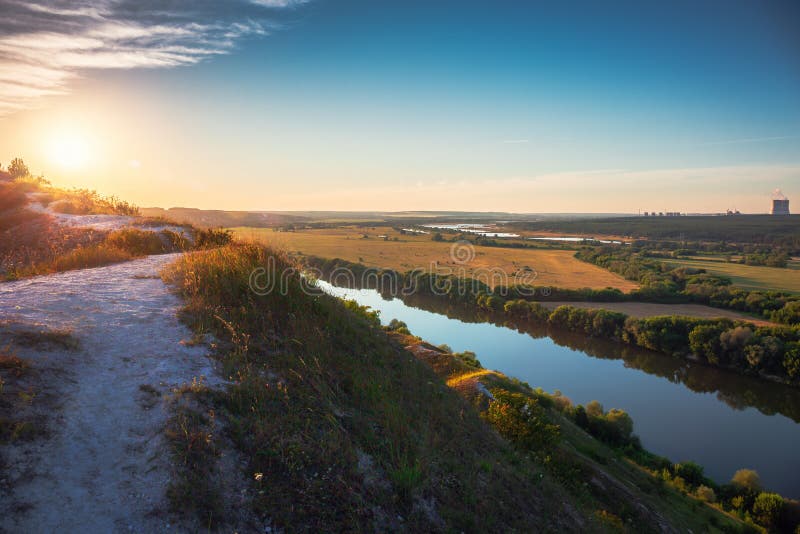 Härlig naturlandskappanorama på solnedgångtid Sikt från det kritakullen eller berget som gör grön ängar och fält med floden arkivfoto Härlig naturlandskappanorama på solnedgångtid Sikt från det kritakullen eller berget som gör grön ängar och fält med floden arkivfoto