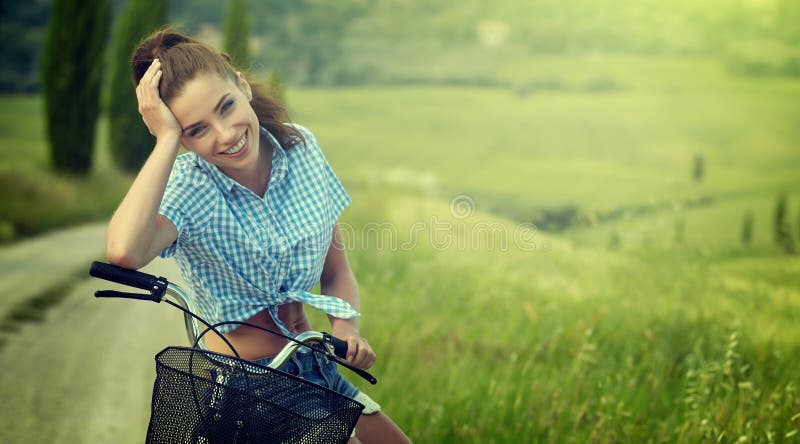 Härlig tappningflicka som sitter bredvid cykeln, sommartid royaltyfri fotografi Härlig tappningflicka som sitter bredvid cykeln, sommartid royaltyfri fotografi