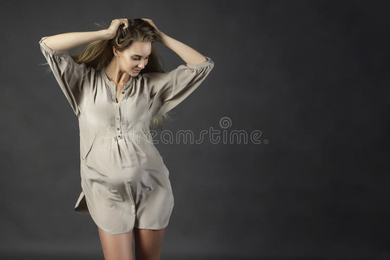 Härlig ung gravid kvinnablondin som bär en kort ljus gra royaltyfri fotografi Härlig ung gravid kvinnablondin som bär en kort ljus gra royaltyfri fotografi