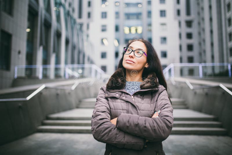 Härlig ung kvinna av europeisk etnicitet med långt brunetthår som ser för att sid och up, bärande exponeringsglas och lagställnin arkivfoto