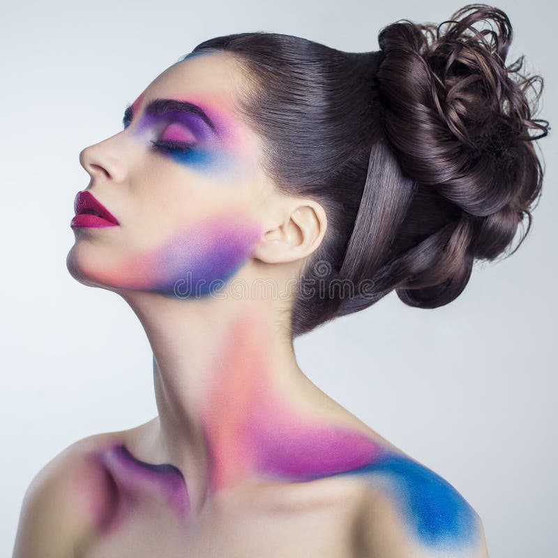 Härlig ung kvinna med idérik kulör makeup och lockig samlad frisyr och målad kulör kropp