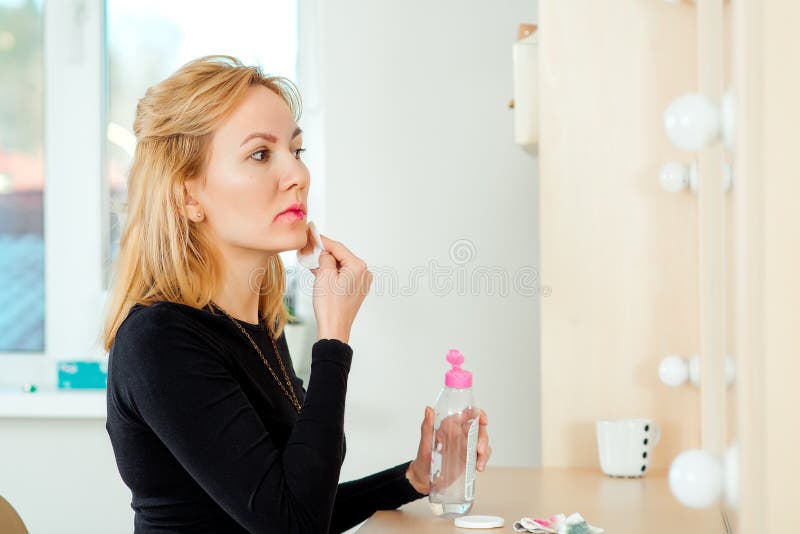 Härlig ung kvinna som tar bort makeup från hennes framsida royaltyfri fotografi Härlig ung kvinna som tar bort makeup från hennes framsida royaltyfri fotografi