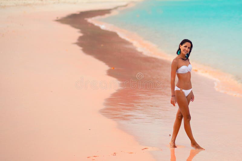 Härlig ung solbränd kvinna i den vita bikinin som poserar på den rosa stranden, ö Lombok, Bali kopiera avst?nd royaltyfri fotografi Härlig ung solbränd kvinna i den vita bikinin som poserar på den rosa stranden, ö Lombok, Bali kopiera avst?nd royaltyfri fotografi