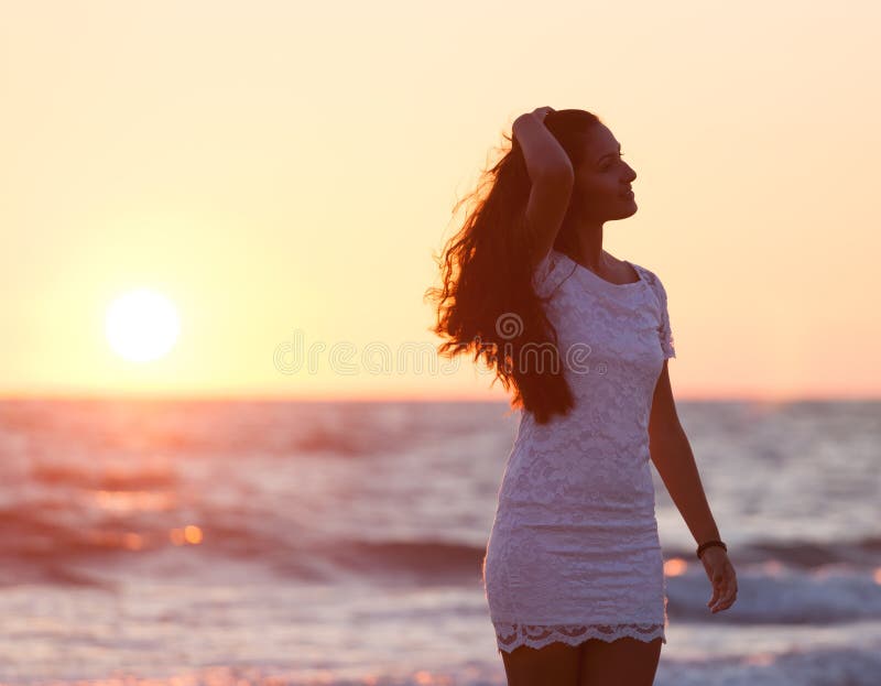 Härlig ung tonåring med en vit klänning på stranden på solar arkivfoto Härlig ung tonåring med en vit klänning på stranden på solar arkivfoto