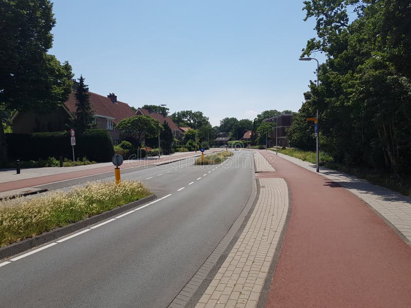 Härlig väl underhållen väg med breda cirkuleringsgränder i Bloemendaal, Nederländerna royaltyfri fotografi Härlig väl underhållen väg med breda cirkuleringsgränder i Bloemendaal, Nederländerna royaltyfri fotografi