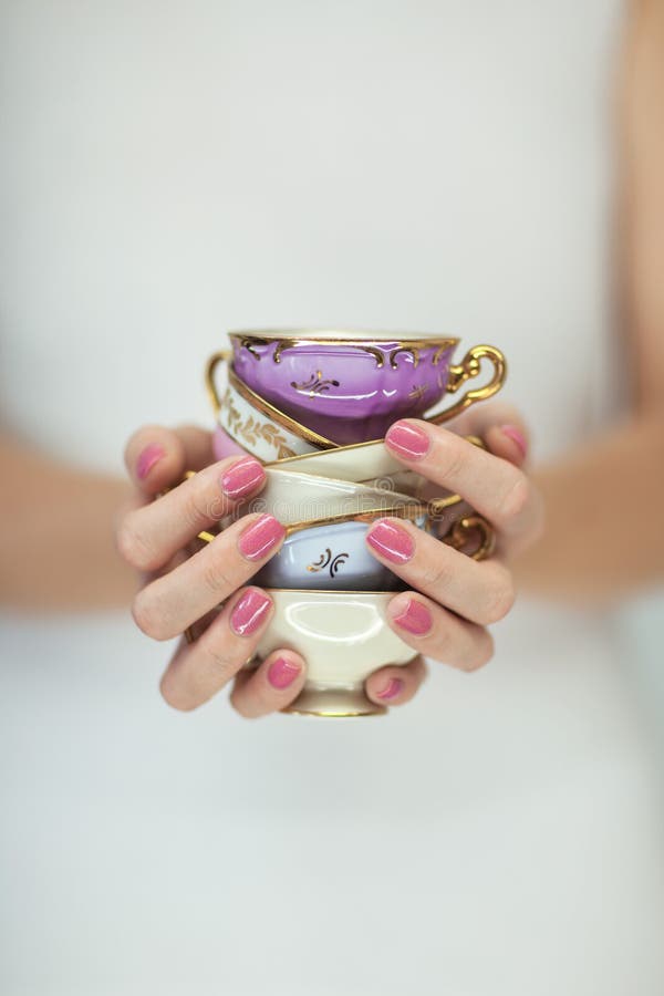 Härliga kvinnahänder med perfekta rosa färger spikar polermedel som rymmer små tappningtekoppar arkivfoto Härliga kvinnahänder med perfekta rosa färger spikar polermedel som rymmer små tappningtekoppar arkivfoto