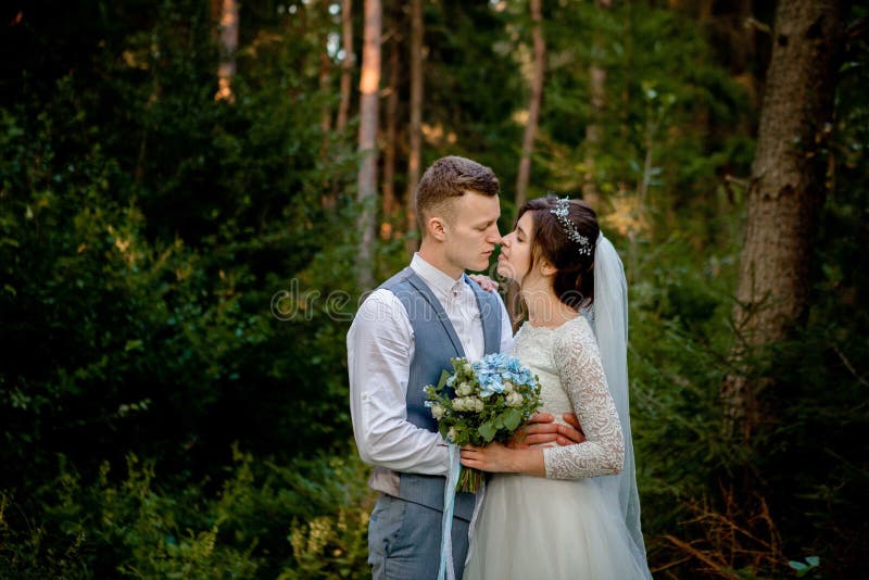 Härliga nygift personpar som går i träna honeymooners Brud- och brudguminnehavhand i pinjeskogen, foto för valentin arkivbilder Härliga nygift personpar som går i träna honeymooners Brud- och brudguminnehavhand i pinjeskogen, foto för valentin arkivbilder