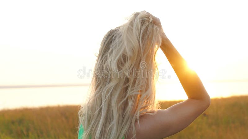 Härligt blont gå i ett fält på solnedgången, närbild stock video