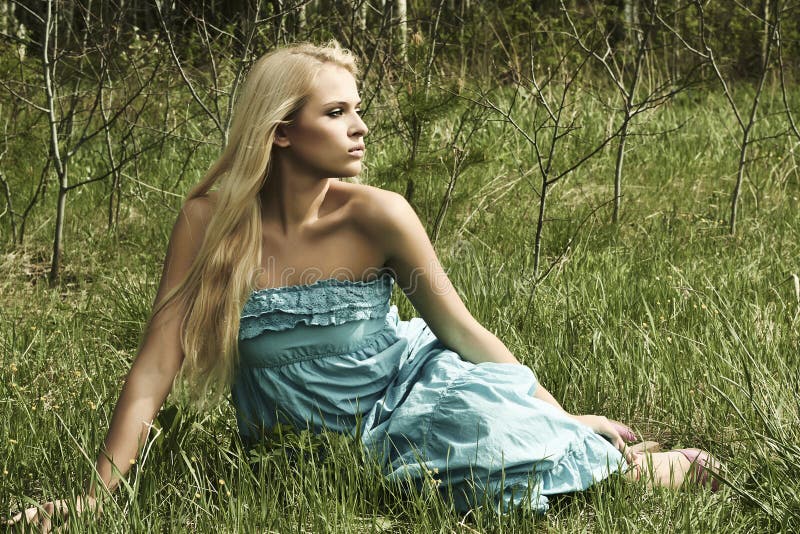 Härligt blont kvinnasammanträde på grönt gräs arkivbilder Härligt blont kvinnasammanträde på grönt gräs arkivbilder